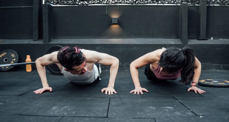Two adults doing push-ups in an indoor gym setting in Mexico City, promoting a fit and healthy lifestyle.